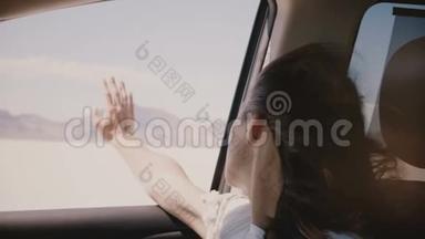 特写镜头的快乐放松的女人，头发在风中吹起，眼睛闭在车里，在盐湖沙漠快速移动。